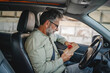 © Miljan Živković - Senior mature man sit in the car and hold small gift with red ribbon