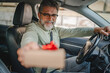 © Miljan Živković - Senior mature man extend hand from the car window with small gift