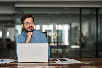 Happy professional business man company employee, young busy smiling male businessman entrepreneur or worker looking away using laptop computer technology working at corporate office desk.