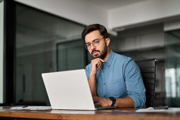 Young professional busy business man executive leader using laptop working in office, busy ceo businessman software engineer thinking looking at computer analyzing online financial market at work.