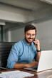 © insta_photos - Busy happy young Latin business man talking on phone using laptop computer in office. Smiling hispanic businessman making call on mobile cellphone, consulting client having work conversation. Vertical