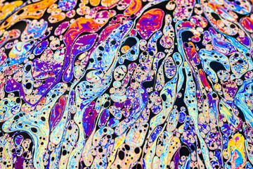 Real photograph of a colorful light interference on a soap bubble surface with random swirls, curves and lines