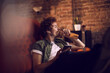 © Marko Geber - Man relaxing on couch drinking beer and listening to music with headphones