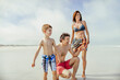 © Marko Geber - Happy family walking on the beach with kids playing and enjoying summer vacation