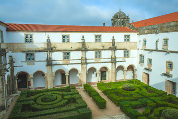 Wall Mural - courtyard within a historic monastery, featuring a symmetrical layout with arched cloisters, manicured hedges, and a central garden, creating a serene and contemplative atmosphere.