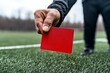 © PaulShlykov - Referee shows red card to player during intense soccer match in a local stadium on a cloudy day
