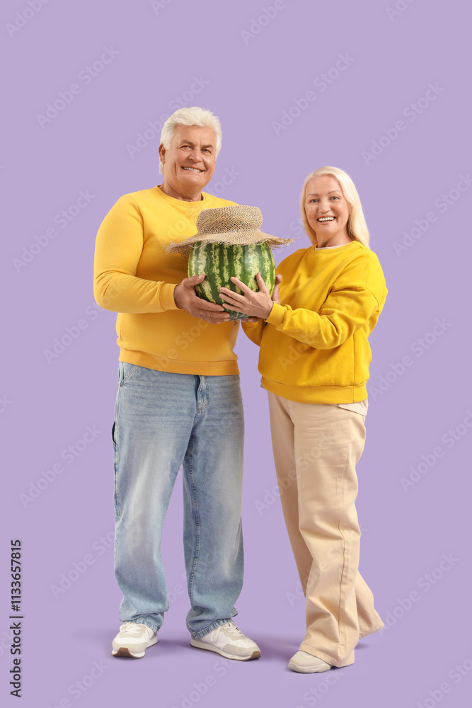Mature couple with watermelon in straw hat on lilac background