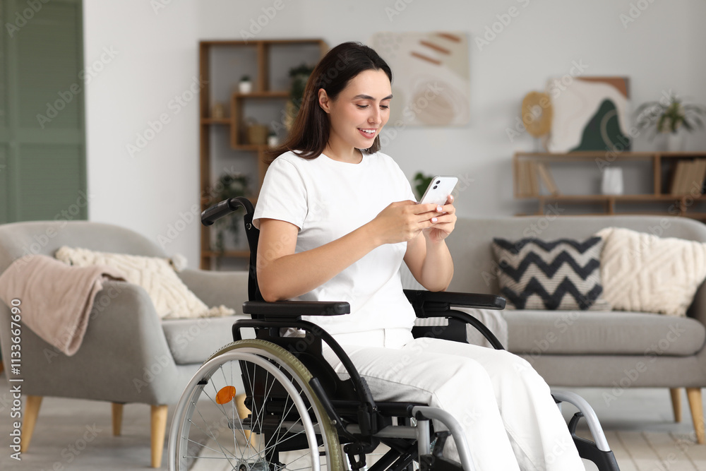 Young woman in wheelchair using mobile phone at home