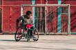 © Nano - Young Latino athlete in wheelchair, training, playing and concentrating with basketball in a city park outdoors