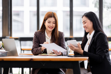 Wall Mural - Business financing accounting banking concept. Two asian Business doing finances and calculate on desk about cost at workplace. Business working on desk with using calculator, finance accounting.
