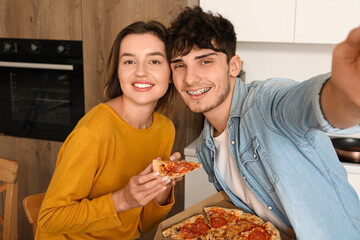 Wall Mural - Young couple with pepperoni pizza taking selfie in kitchen