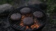 © BOCAH - Four burgers cooking on a grill outdoors.