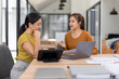 © David - Happy two asian female freelance entrepreneurs reading and planning analyzing the financial report, business plan investment,  on computer while working together in the office.