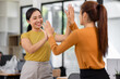 © David - Happy business asian people are keeping arms raised hi five and expressing joyful while standing in workplace office. achieving goals.