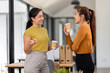© David - Two asian happy businesswomen talking during coffee break in modern office or coworking space. relaxing and talking after working time, business and people partnership concept