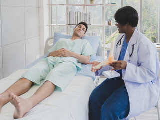 Wall Mural - Portrait patient caucasian man with woman doctor nurse carer physical therapist black people two person sitting talk helping support give advice and holding relax check on leg body inside hospital