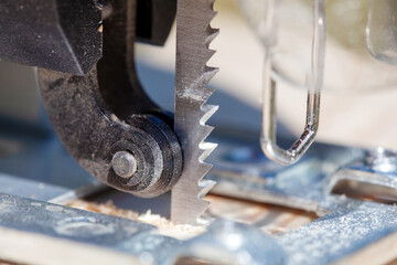 The builder works with a jigsaw. The craftsman cuts the board with a jigsaw.