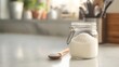 © cynz - A closeup of a jar of Himalayan salt next to a wooden spoon, sitting on a clean counter, representing mindfulness and purity
