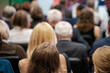 © Anton Gvozdikov - People sitting in rows, listening attentively during a business or educational conference.