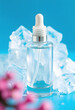 © Go - Transparent glass cosmetic bottle with crisp ice cubes on a vivid blue background, clear beauty product packaging for branding and packaging, blurry foreground, with white tones