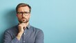 © nattapon98 - A thoughtful man with glasses poses against a blue background, displaying a contemplative expression.