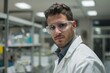 © Tanu - A focused male scientist wearing protective glasses and a lab coat analyzes samples in a well-equipped laboratory, showcasing a diligent research atmosphere.