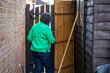 © Tosh Lubek - Woman wearing Green Top Storing Weed Whacker Strimmer and Garden Broom in Shed