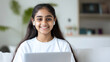 © Ari - Indian girl online in living room holding a laptop and earphones