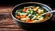 © familymedia - A vibrant vegetable noodle soup served in a textured ceramic bowl, with slices of carrots, green onions, and herbs evoking the flavors of homemade comfort and warmth.