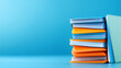 © Fareedoh - Stack of colorful books against a vibrant blue background, showcasing creativity and education.