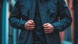 © jambulart - Person adjusts dark jacket outdoors.