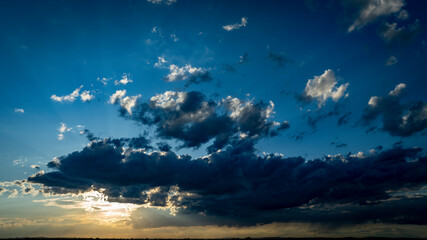 Wall Mural - A stunning display of colors fills the sky as the sun sets, casting shadows on the clouds and creating a tranquil atmosphere during the evening hours.