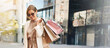 © peopleimages.com - Woman, shopping bag and smile for fashion in city, reflection and excited for discount in street. Person, banner and summer with sunglasses, sale and deal with walk for commute on road in France