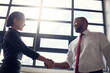 © peopleimages.com - Happy, business people and handshake with interview for hiring, recruiting or partnership at workplace. Businessman, woman or colleagues shaking hands by window for agreement, deal or negotiation