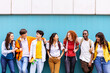 © Xavier Lorenzo - Front view of happy multiracial students standing over isolated blue background. Diverse teenage friends having fun talking leaning on campus building college wall. Education and youth concept