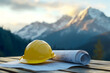 © Pukan - A yellow hard hat rests on blueprints, with majestic mountains in the background, symbolizing construction and planning in a natural setting.