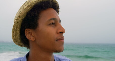 Wall Mural - Young man in straw hat enjoying peaceful ocean view at beach