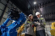 © surachetkhamsuk - Engineer standing by robotic arm and operating machine in industry factory, technician worker check for repair maintenance electronic operation