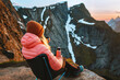 © EVERST - Woman traveling in Norway sitting in camping chair drinking tea with thermos on mountain summit, girl hiking in Lofoten islands alone, adventure vacations getaway healthy lifestyle trip