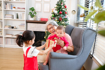 Wall Mural - Little girl giving gift to old woman celebrating Christmas. Christmas concept.