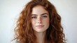 © Olena - Charming Young Woman with Curly Brown Hair Gazing Confidently at the Camera Against a Clean White Backdrop