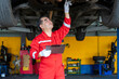 © Verin - asian senior experienced mechanic business owner in uniform checking lifted vehicle in garage service
