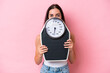 © luismolinero - Young caucasian woman isolated on pink background with weighing machine and hiding behind it