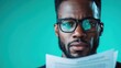 © svastix - A close-up shows a serious man with glasses holding a paper. His focus is evident, suggesting concentration and intelligence against a green backdrop.