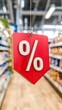 © pvl0707 - Floating red percentage sign in a blurred supermarket aisle highlights exciting deals and discounts