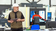 © Grispb - Man manager industrial factory. Specialist with e-tablet stands in workshop. Factory with high-tech equipment. Man owner of manufacturing business. Large CNC milling chamber. Industrial plant manager