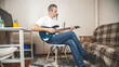 © Mariia - Man playing electric guitar at home