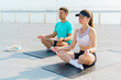 © muse studio - Couple practicing meditation together on a sunny rooftop deck during the morning hours