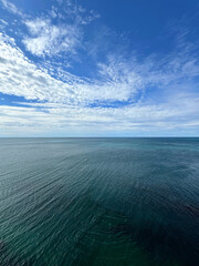 Wall Mural - Calm sea and white clouds in sky.