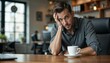 © Alina - Young man in stressed mood sitting at desk with coffee cup in modern office environment